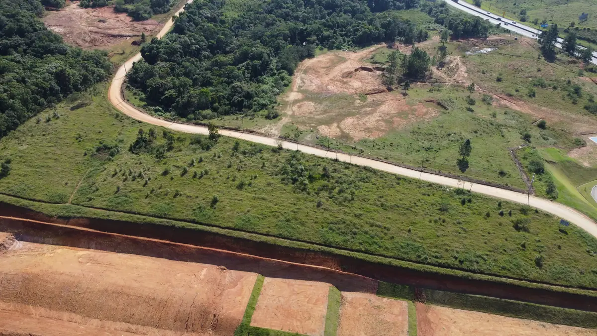 Vista aérea da gleba antes das obras, com o acesso de terra já aberto entre o verde